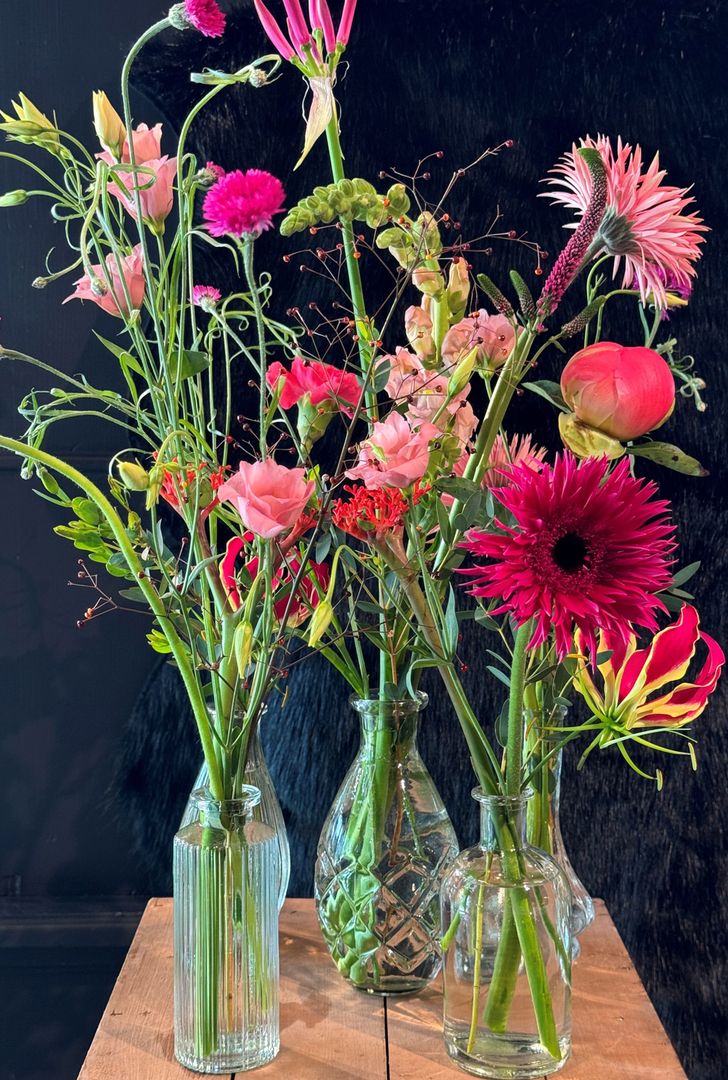 Ein Tisch mit drei Vasen voller bunter Blumen darauf.