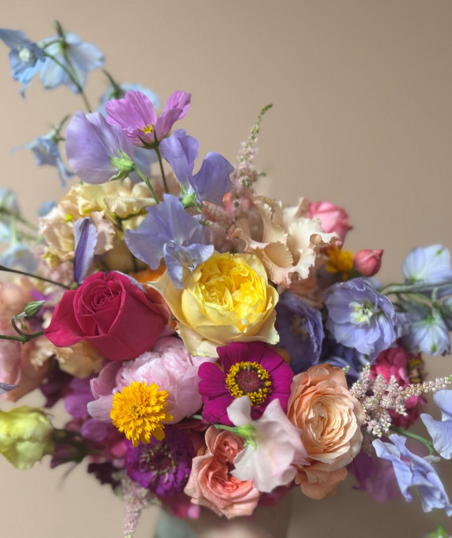 Ein bunter Brautstrauß wird von einer Person in der Hand gehalten.